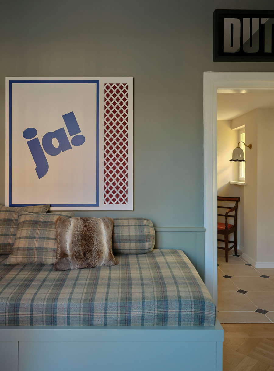 Zu sehen ist hier ein Arbeitszimmer mit einem maßgefertigtem Daybed mit Bezug und Kissen aus Tartanstoff, dekorativem Fellkissen und moderner Typografie-Kunst.